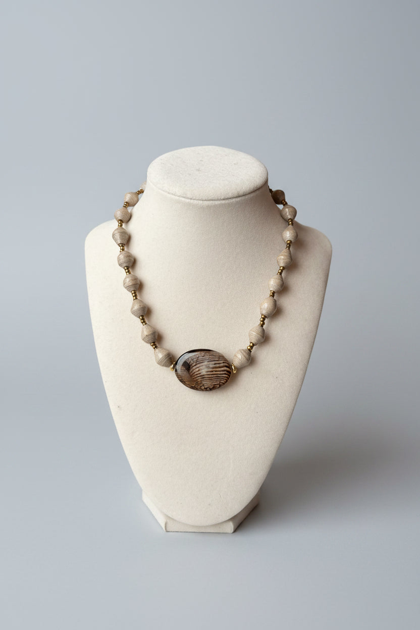 Necklace with large central bead on a white bust against a gray background