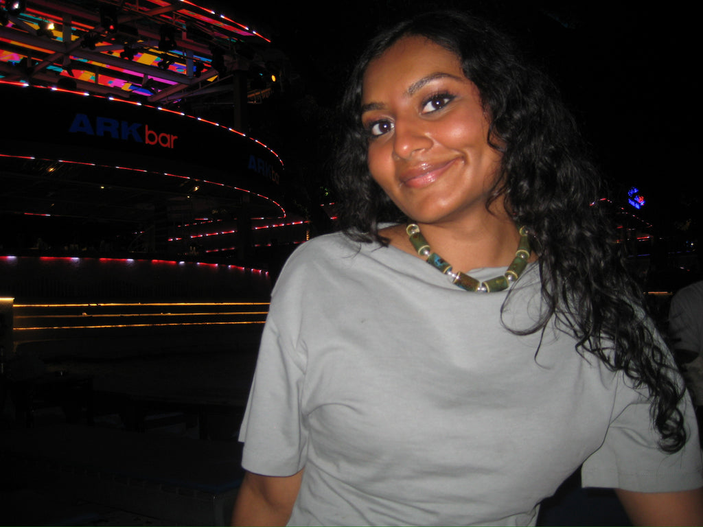Woman in a gray shirt with a blurred background featuring colorful lights