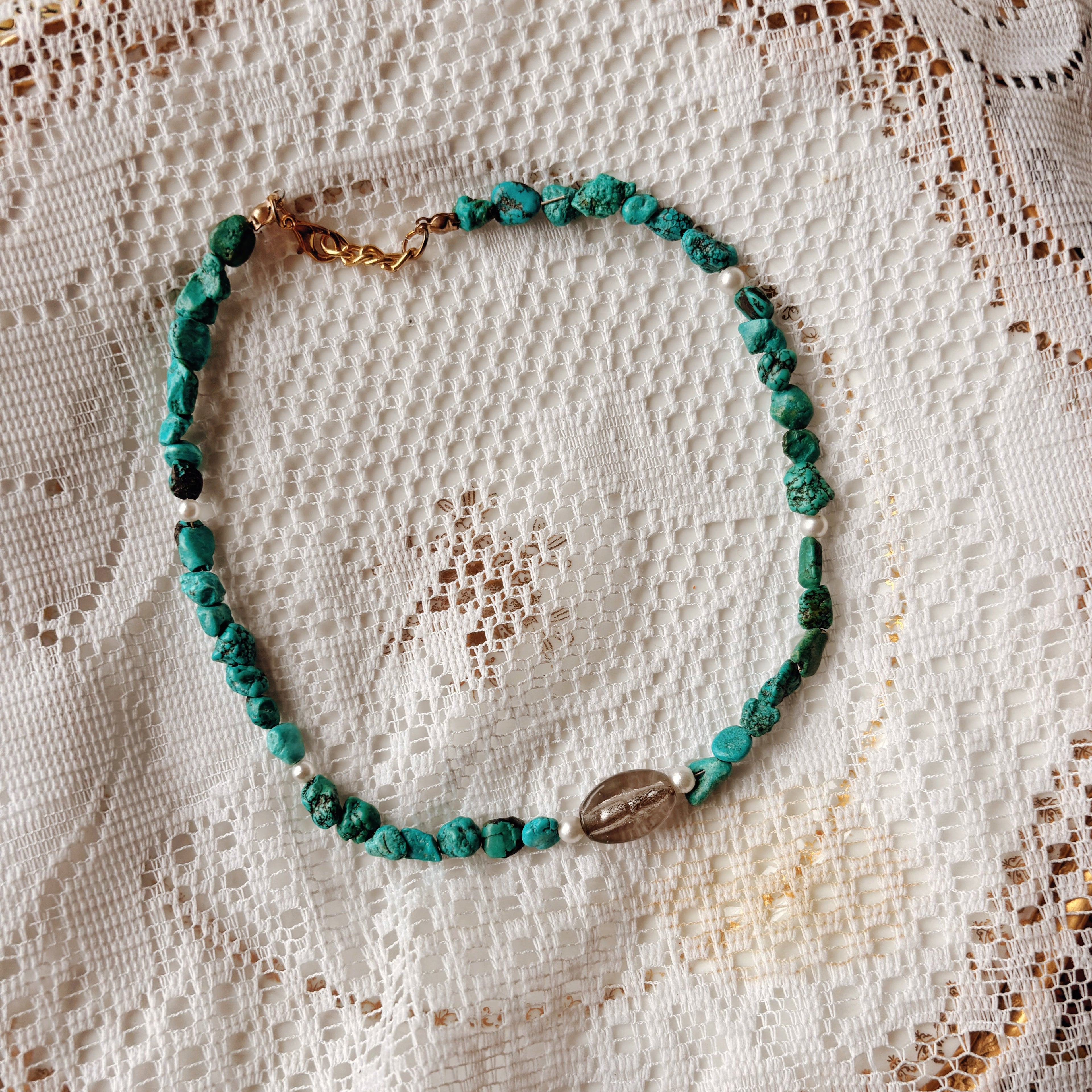 Turquose beaded necklace on a textured white fabric background