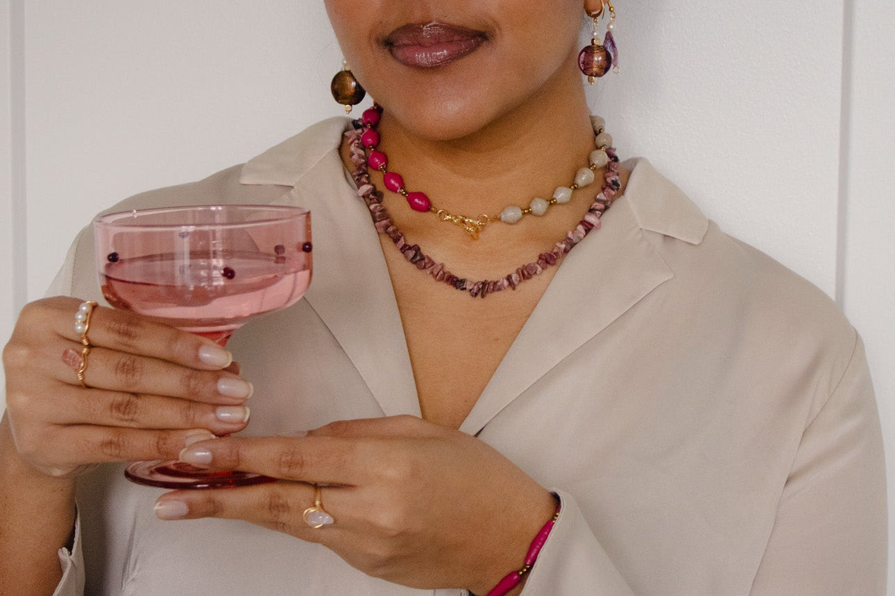 Woman holding a glass of pink wine against a white background