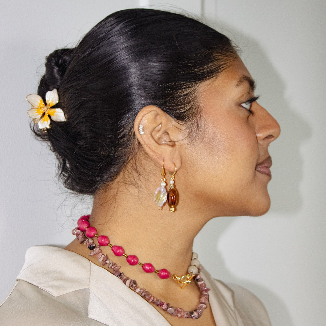Woman wearing a necklace and earrings with a neutral background
