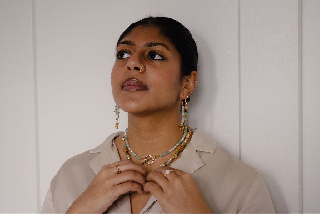 Woman wearing a necklace against a white paneled wall