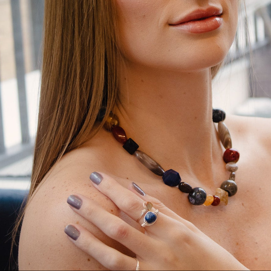 Woman wearing a colorful beaded necklace indoors with a blurred background