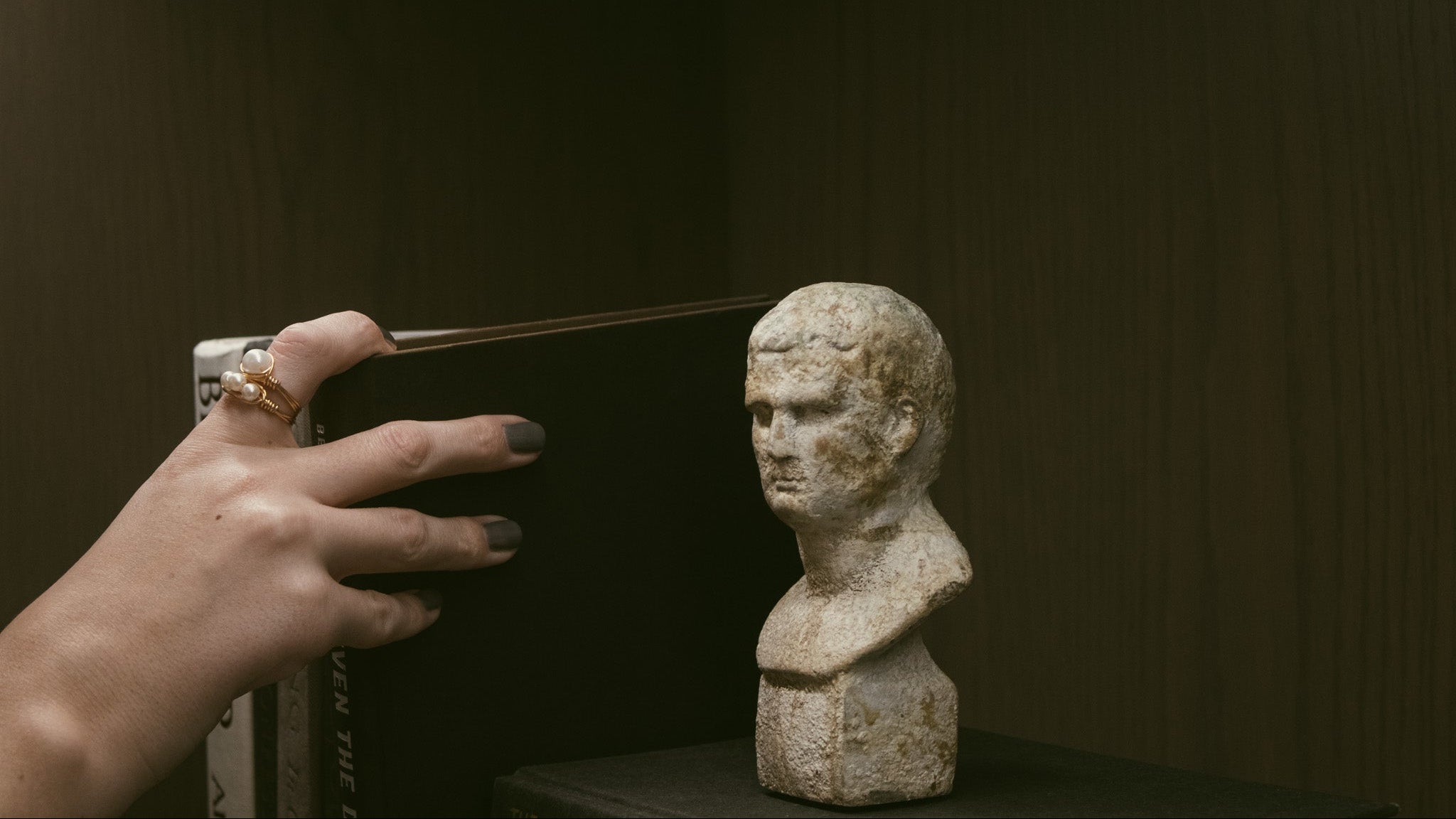 Person taking a photo of an ancient stone bust with a smartphone.