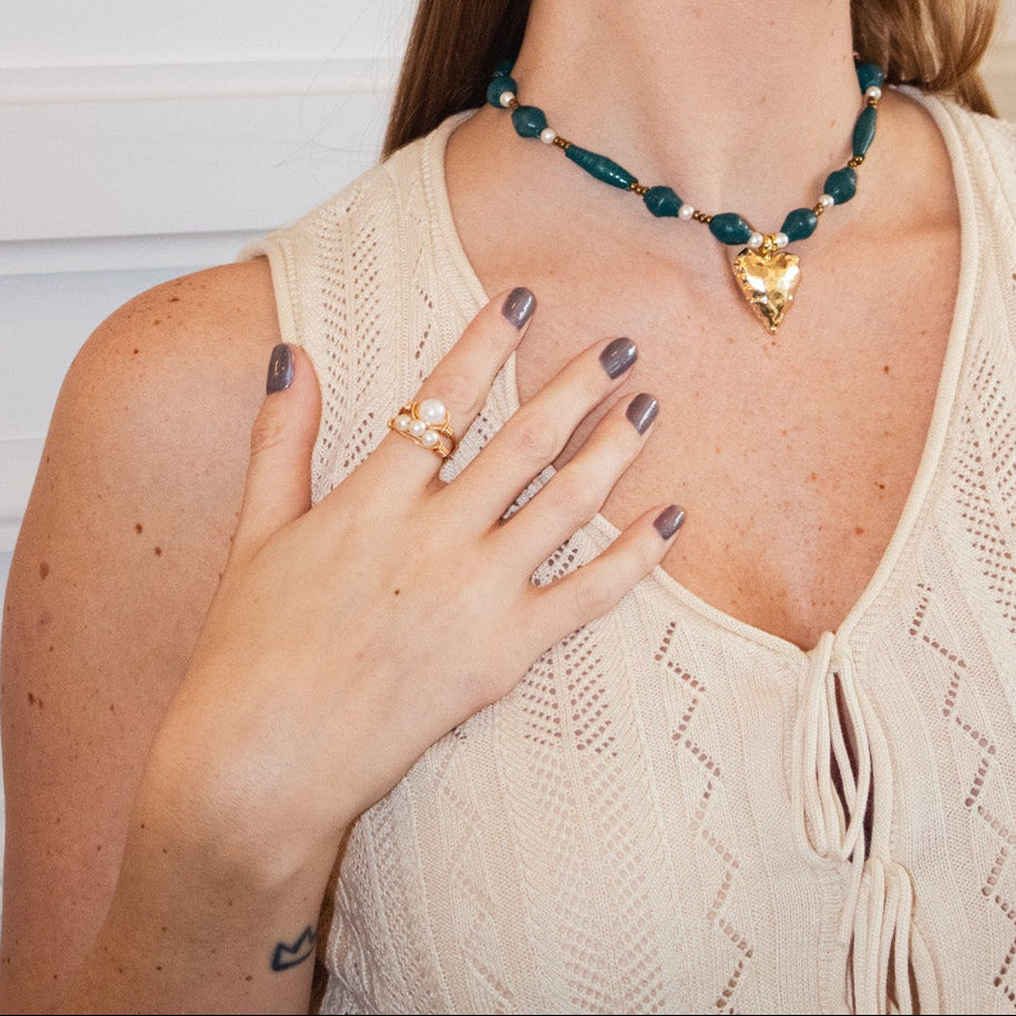 Woman wearing jewelry in a room with a framed poster on the wall.