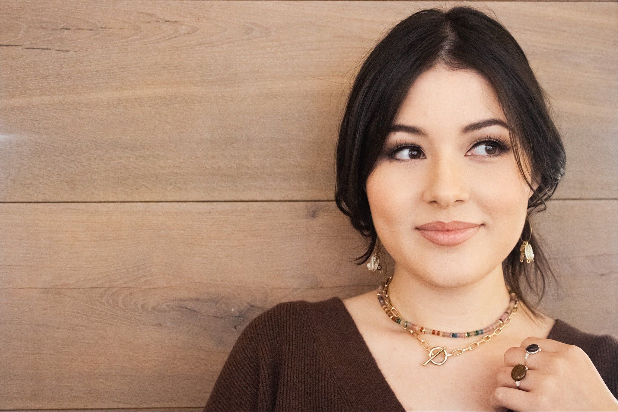 Woman wearing a necklace and earrings against a wooden background