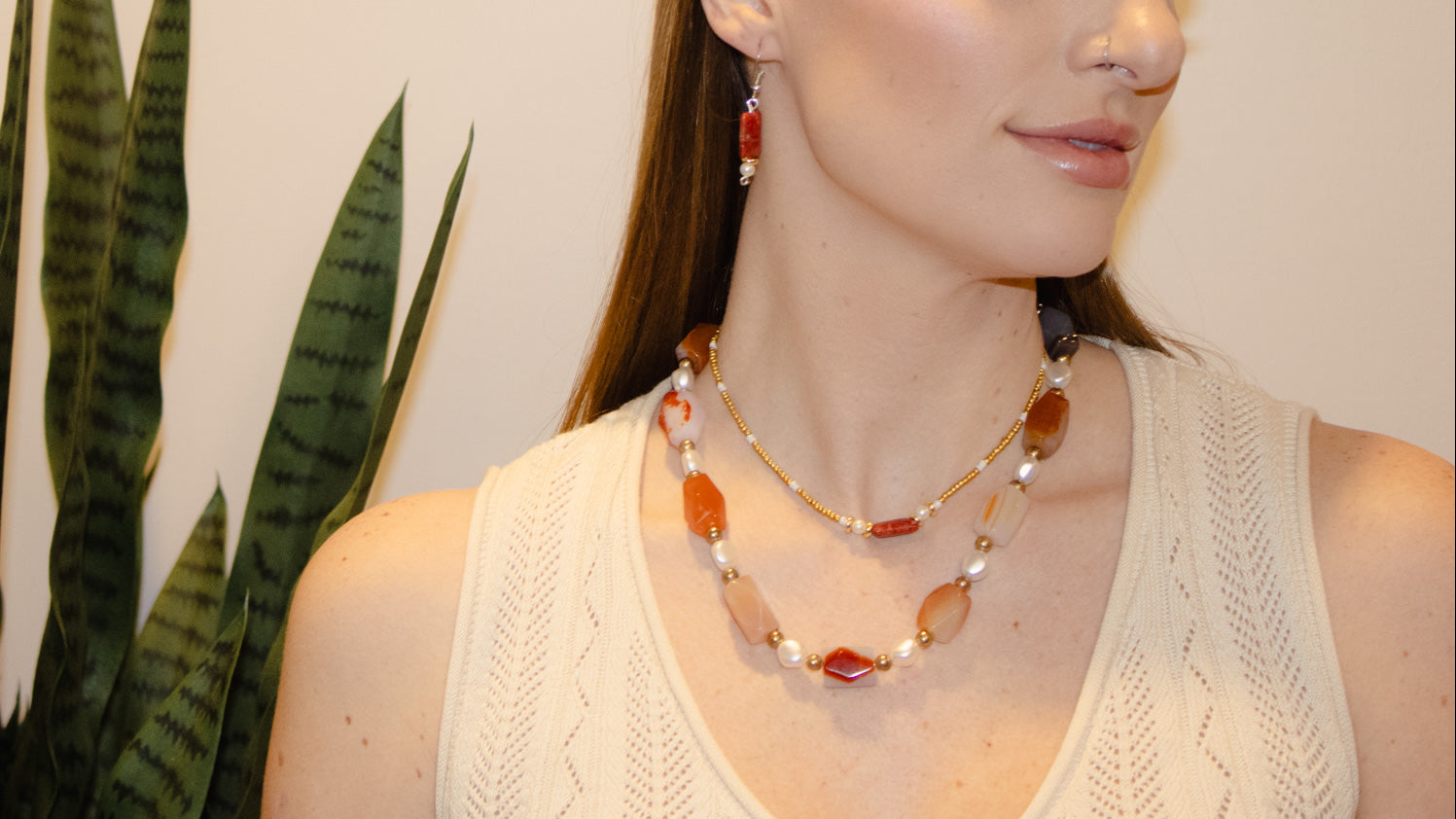 Woman wearing a necklace in front of a plant