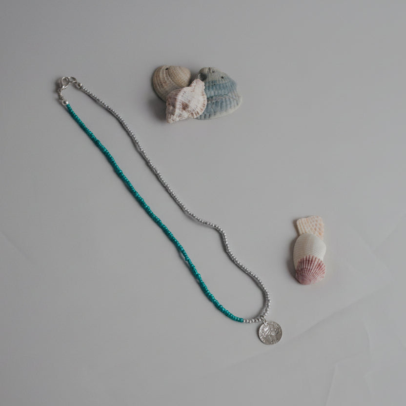 Necklace with a pendant on a textured surface with seashells