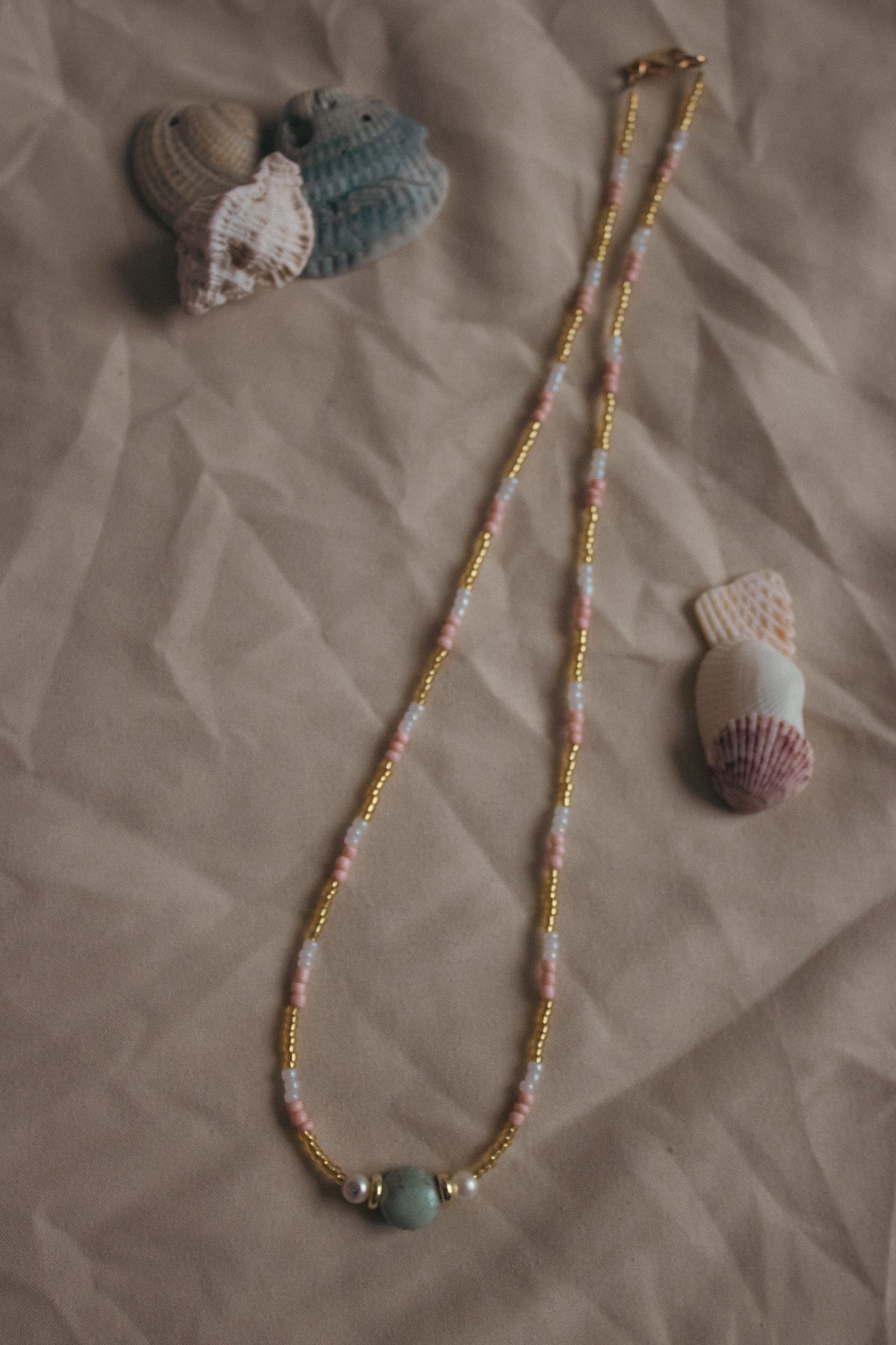 Beaded necklace with seashells on a textured surface