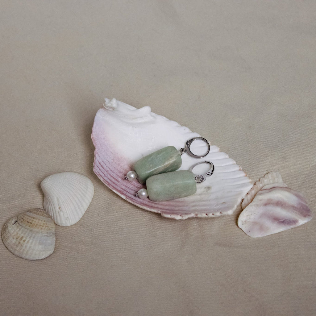 Jewelry set with stones on a seashell against a beige background