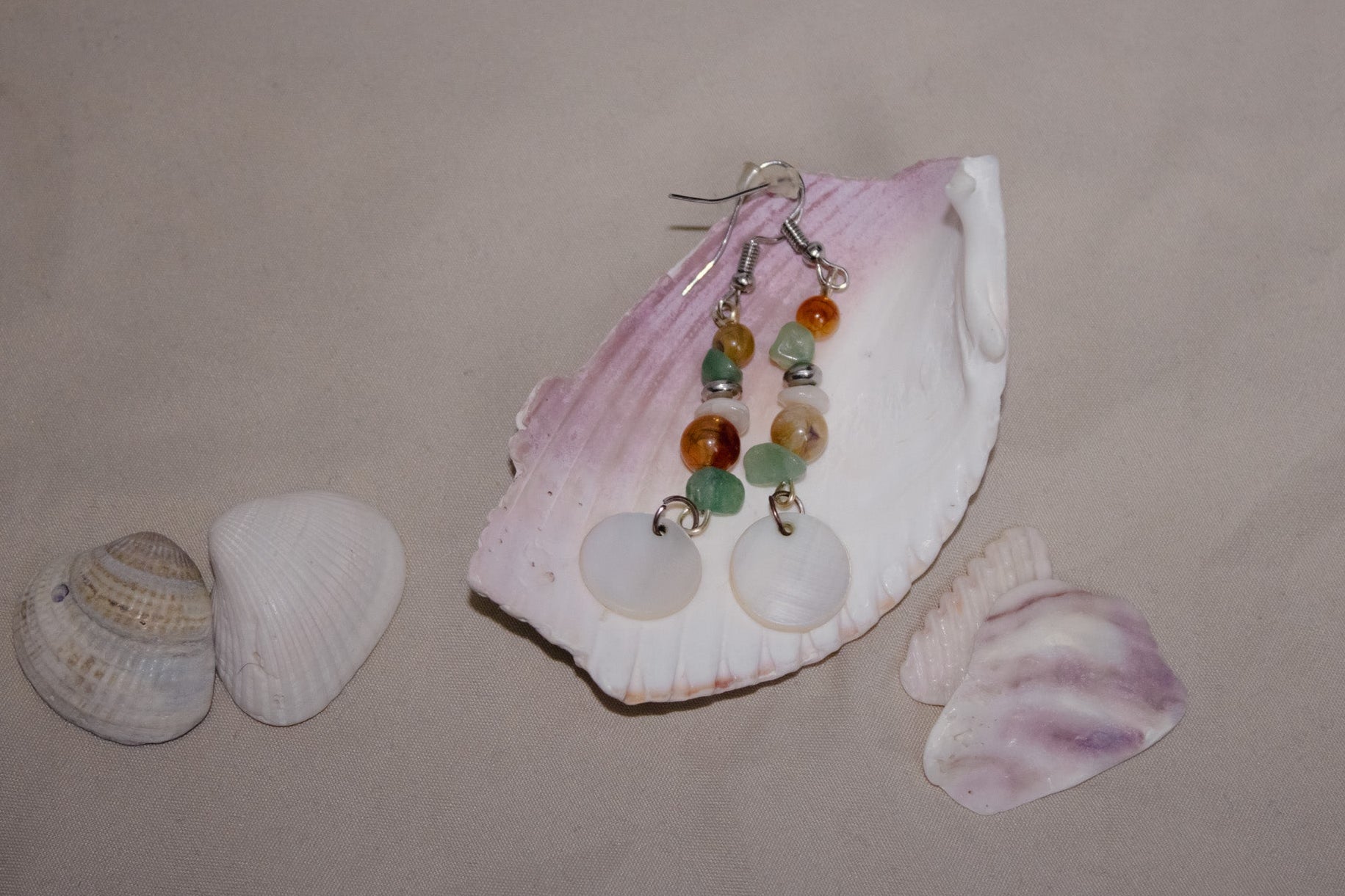 Jewelry set with earrings and a shell on a beige background