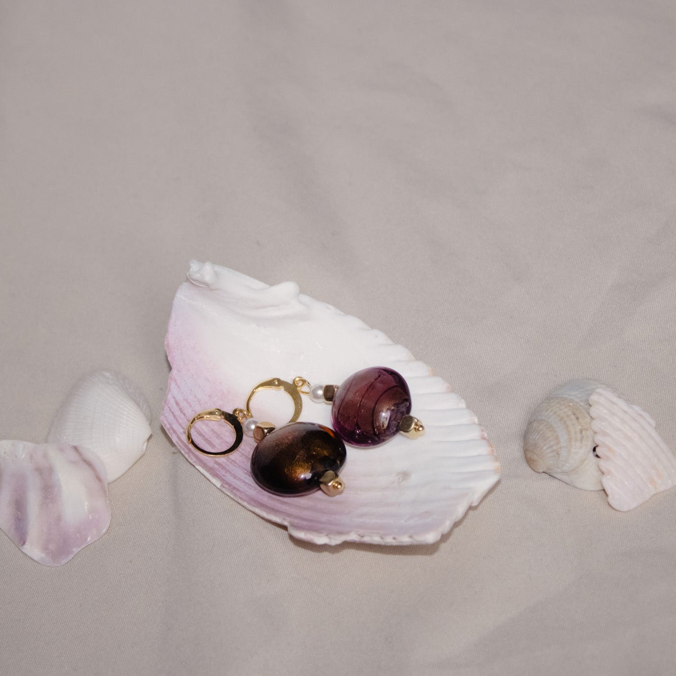 Jewelry set with purple beads and gold accents on a white shell against a gray background
