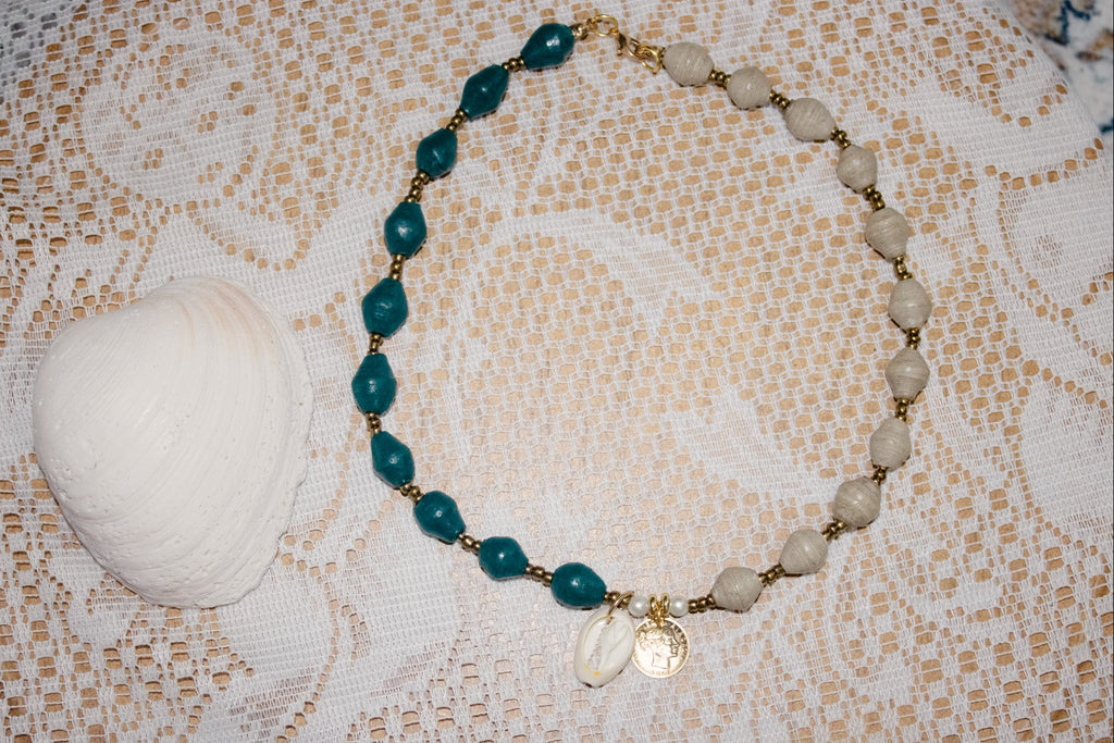 Necklace with green and beige beads on a textured fabric background