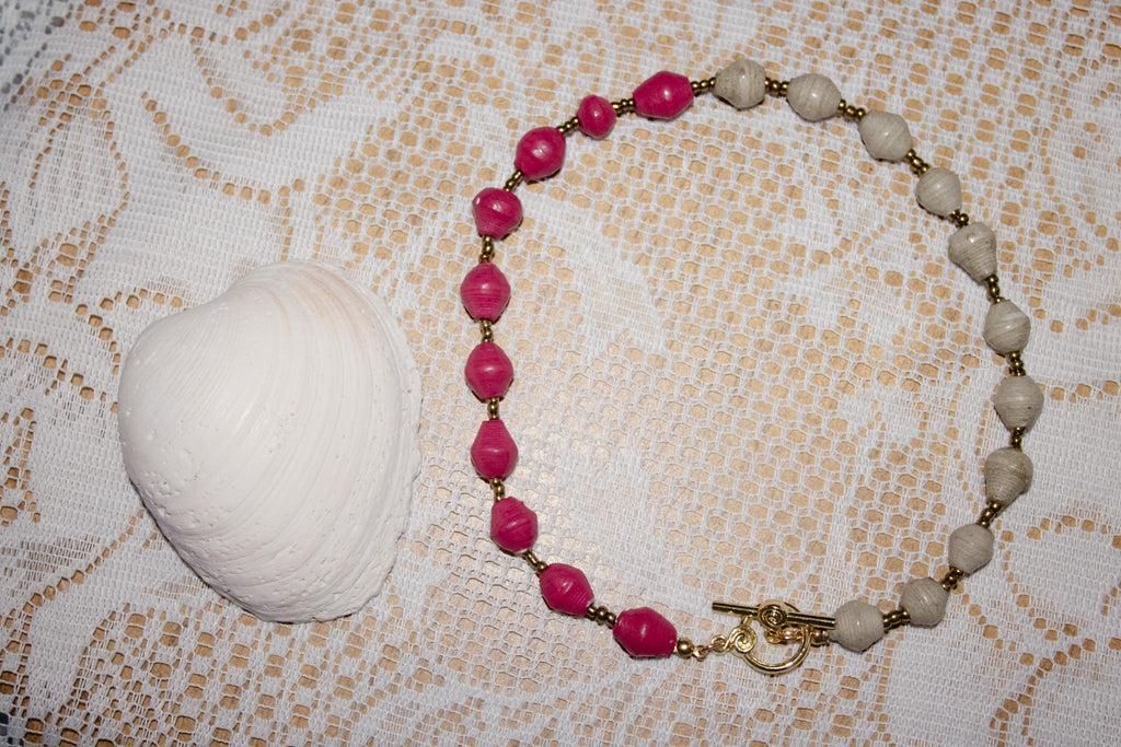 Bracelet with pink and beige beads on a textured fabric background