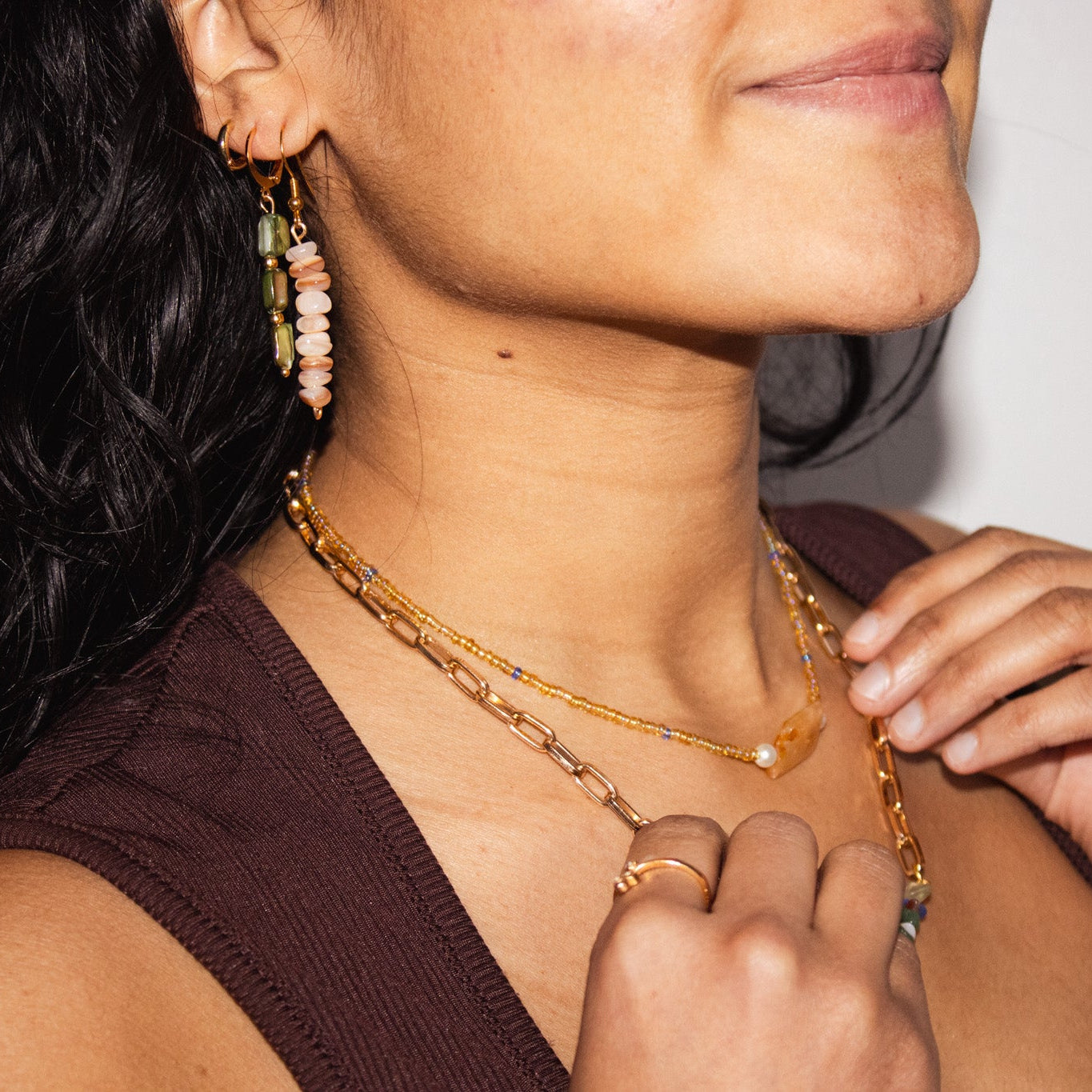 Close-up of a person wearing a gold chain necklace and earrings.