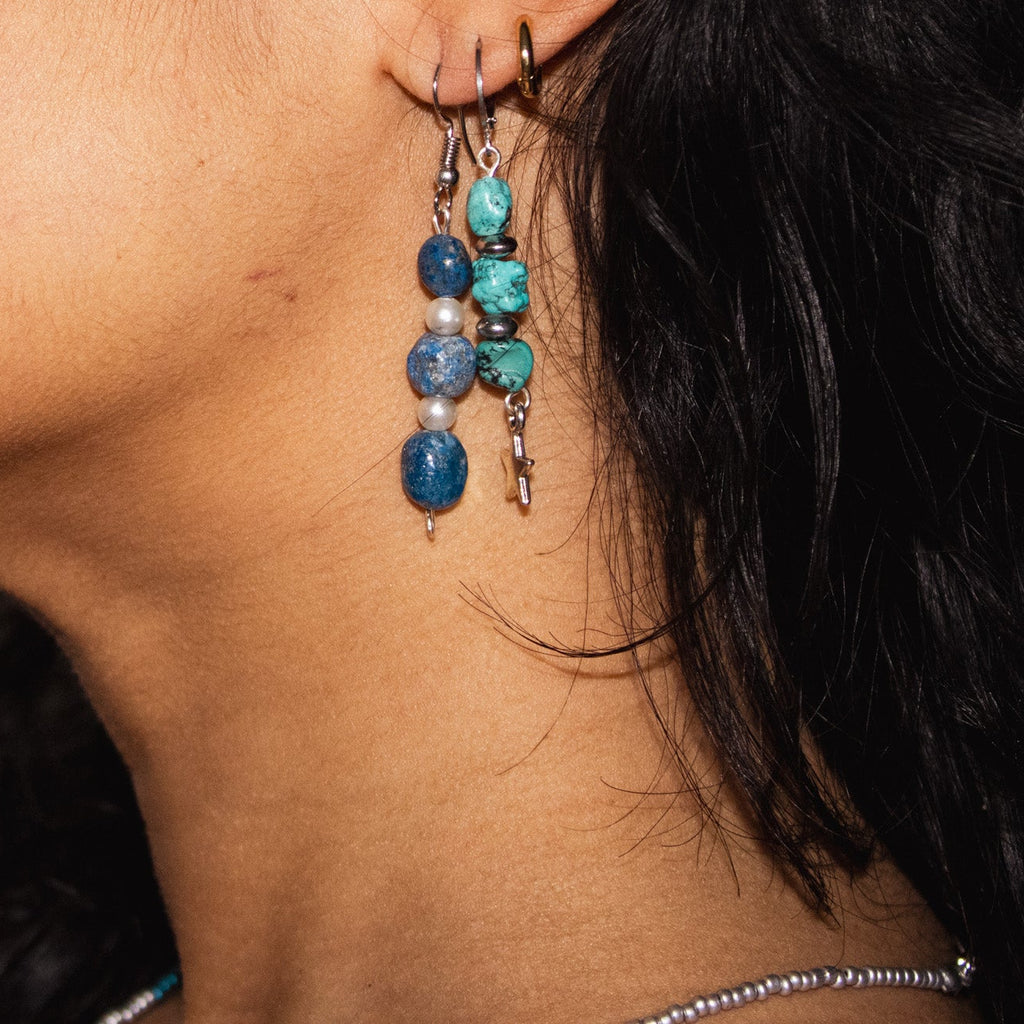 Close-up of a person wearing a beaded earring with blue and silver beads.